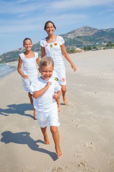 Adorable happy boy with his sisters running on beach vacation