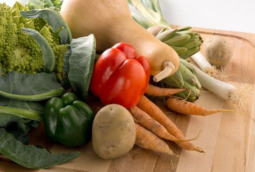 A groupo of fresh vegetables on a wooden cutting board.