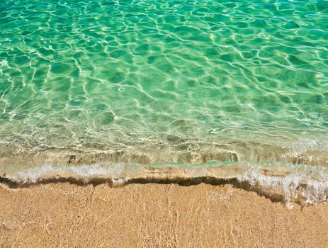 Clear turquoise water washing up onto sandy beach in Sardinia