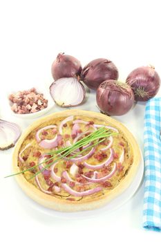 Onion tart with leeks and bacon on a light background