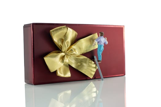 puppet man making the golden bow on the red christmas present