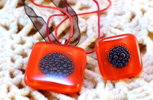 origina red glass handmade ring and amulet on knitted background 