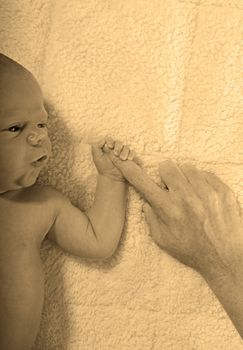 newborn baby holding mother's finger