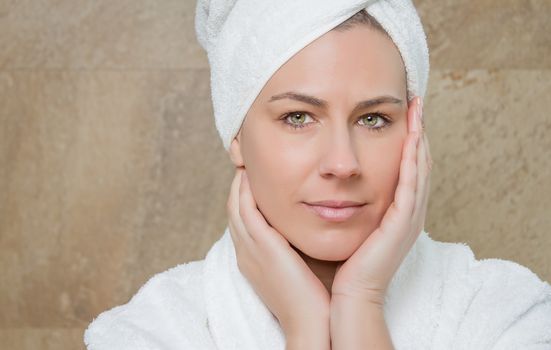 Portrait of beautiful young woman wearing a white bathrobe on the bathroom