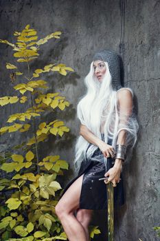 Attractive gray-haired maiden warrior in armor with sword in hand