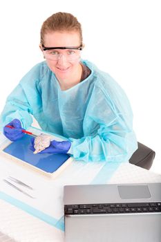 Female pathologist or medical technologist seated at a desk in the laboratory working on a dissection of tissue for an in vitro or post mortem diagnosis