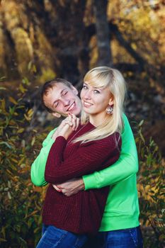 Young couple tenderly and lovingly embrace each other in autumn park