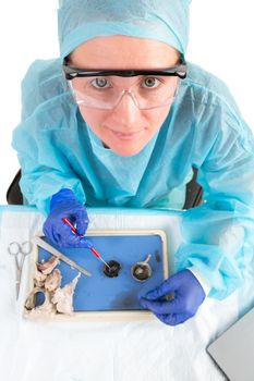 Female pathologist or medical technologist conducting tissue analysis in the laboratory on diseased or post mortem samples, high angle view