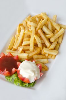 a pile of appetizing french fries on white plate with tomato sauce and cream sauce