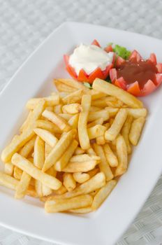 a pile of appetizing french fries on white plate with sauce