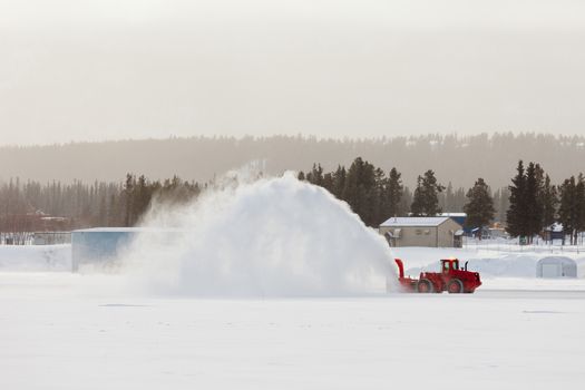 Snow thrower truck clearing road after whiteout winter snowstorm blizzard for vehicle access