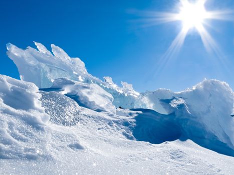 Icy heap of ice chunks of glacier with some fresh snow and blue sunny sky melting it away