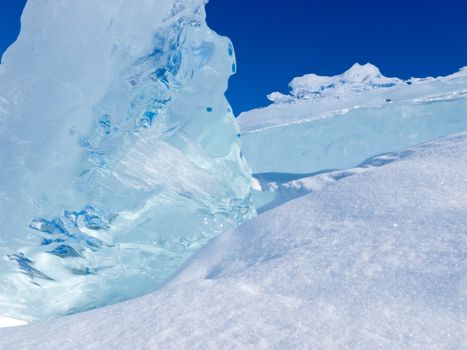 Clean clear ice chunks of glacier piled up with some fresh snow and blue sunny sky