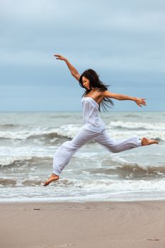 Woman jumping on the beach in front of the sea