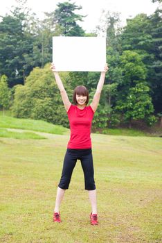 Asian girl holding a white blank card at outdoor park