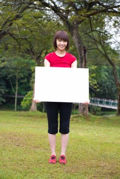 Happy Asian girl holding a white blank card at outdoor park
