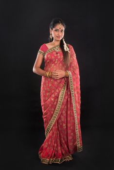 Full body traditional Indian girl in sari costume standing isolated on black background.