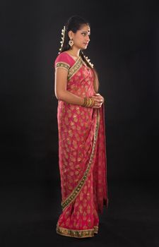 Full body traditional young Indian girl in sari costume standing isolated on black background.