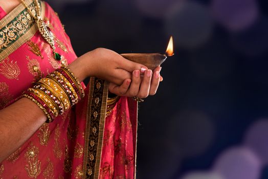 Diwali or deepavali photo with female hands holding oil lamp during festival of light