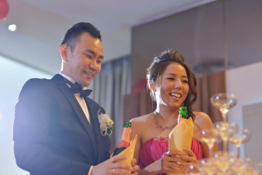 Happy Asian Chinese wedding dinner reception, bride and groom champagne toasting, natural candid photo.