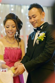 Bride and groom cake cutting, natural candid photo. Asian Chinese wedding dinner reception.