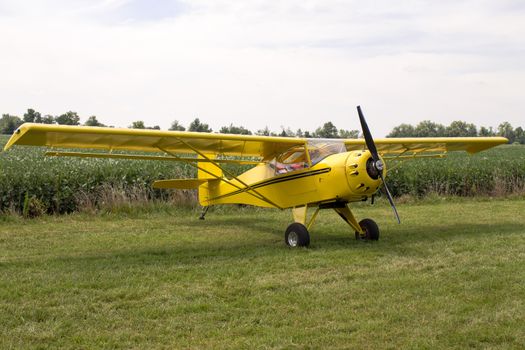 Single engine fixed wing aeroplane parked on a green grass field on display during a rural airshow