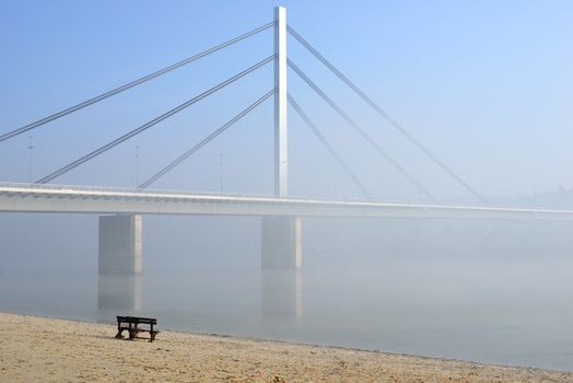 Winter day on Danube river with bridge in fog