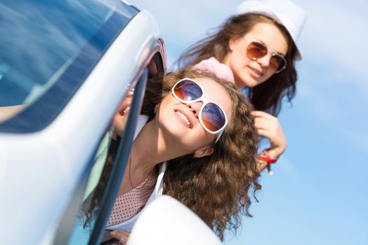 young attractive woman in sunglasses got out of the car window and laugh