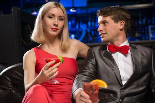 couple in a nightclub on the couch with a drink, have fun