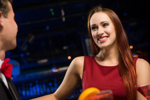 portrait of a woman in a nightclub, sitting on the couch and talking with man