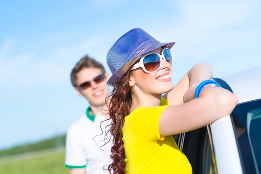 young attractive woman in sunglasses and hat stands next to a car, a close-up portrait