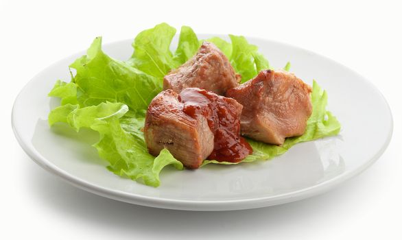 Three pieces of roasted meat with fresh lettuce and tomato sauce on the white plate