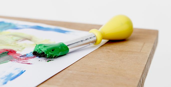 green paint with paint brush  and paper on wooden table