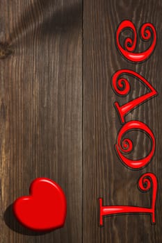 The red heart and the inscription love on the wooden background