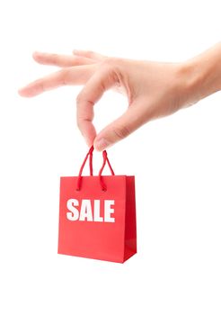 Hand holding a miniature red shopping bag with retail sale advert 