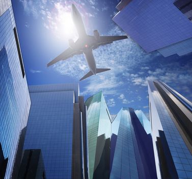 passenger plane flying ove rmodern office building against blue sky white cloud seem city life and air transport business scene