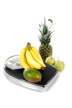 a weighing scale with fruits on a white background