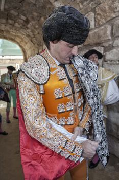 Ubeda, Jaen province, SPAIN - 29 sebtember 2010: Spainish bullfighter Jose Manuel Montoliu with orange dress and silver putting itself the walk cape before initiating the inaugural procession in the Bullring of Ubeda, Jaen province, Andalusia, Spain