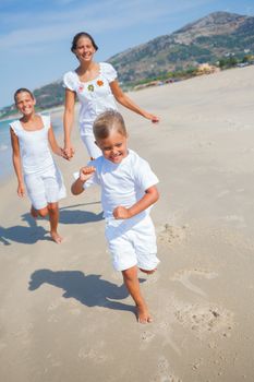 Adorable happy boy with his sisters running on beach vacation