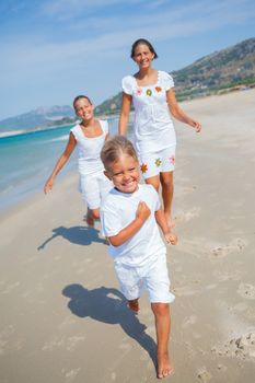 Adorable happy boy with his sisters running on beach vacation