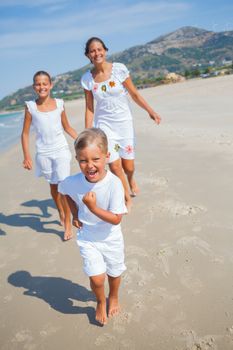 Adorable happy boy with his sisters running on beach vacation