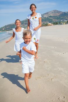 Adorable happy boy with his sisters running on beach vacation