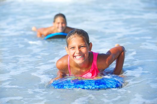 Summer vacation - Two cute girls having fun with surfboard in the ocean