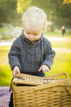 Adorable Little Blonde Baby Boy Opening a Picnic Basket Outdoors at the Park.
