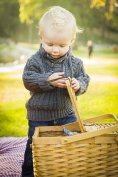 Adorable Little Blonde Baby Boy Opening a Picnic Basket Outdoors at the Park.
