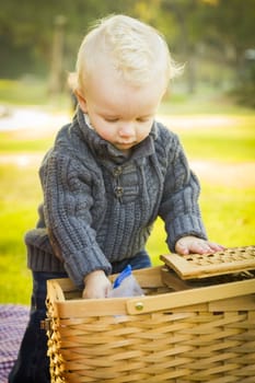 Adorable Little Blonde Baby Boy Opening a Picnic Basket Outdoors at the Park.
