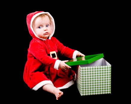 Cute little baby girl wearing Christmas costume, on black background.
