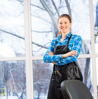 portrait of a woman in a barber shop barber worth apron crossed her arms