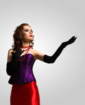 young attractive woman in corset and red dress raised her hand and looks at it