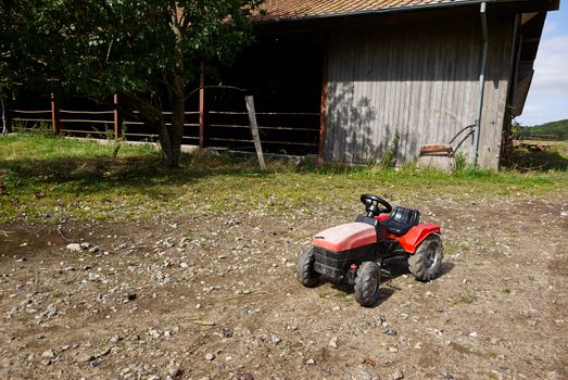 Kids children's plastic toy tractor in a big agriculture farm